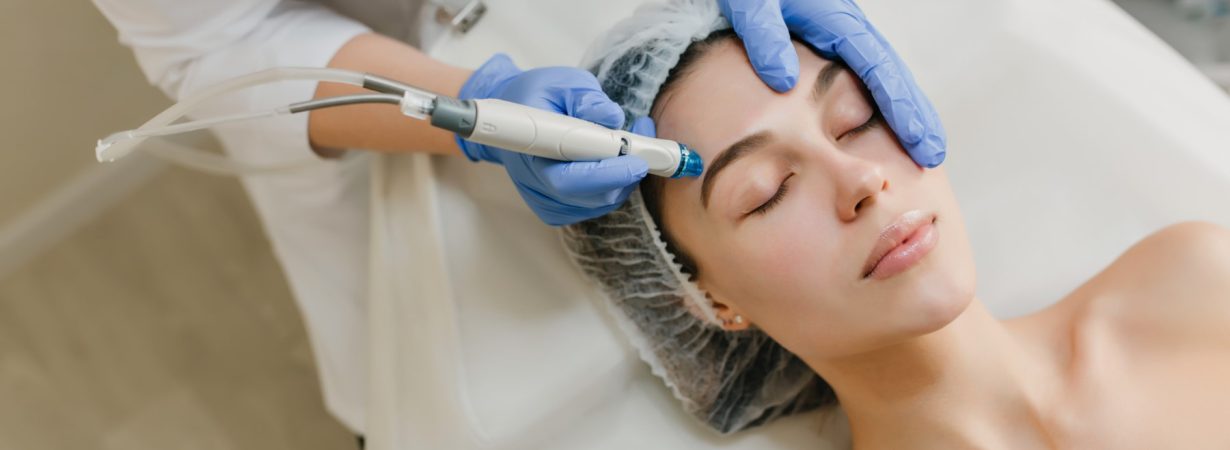 View from above rejuvenation of beautiful woman enjoying cosmetology procedures in beauty salon. Dermatology, hands in blue glows, healthcare, therapy, botox